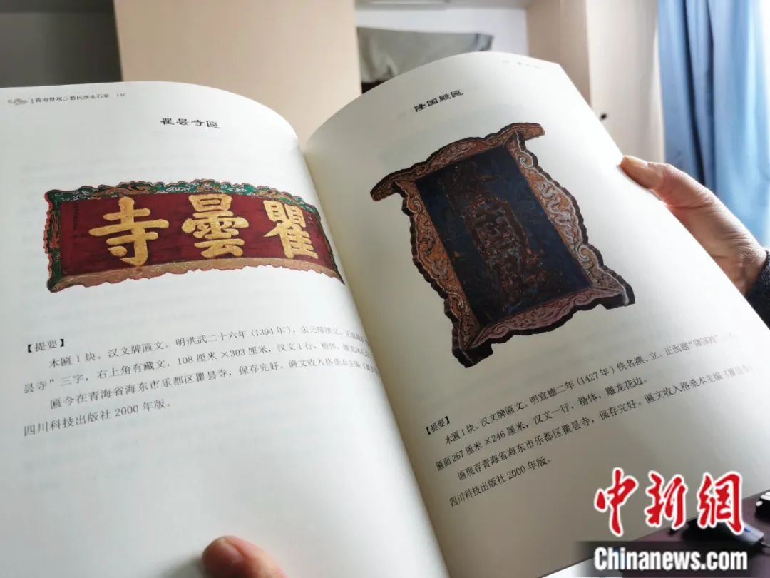 古籍保护人员展示介绍明代朱元璋撰写的青海瞿昙寺匾(左)的出版书籍。张添福 摄